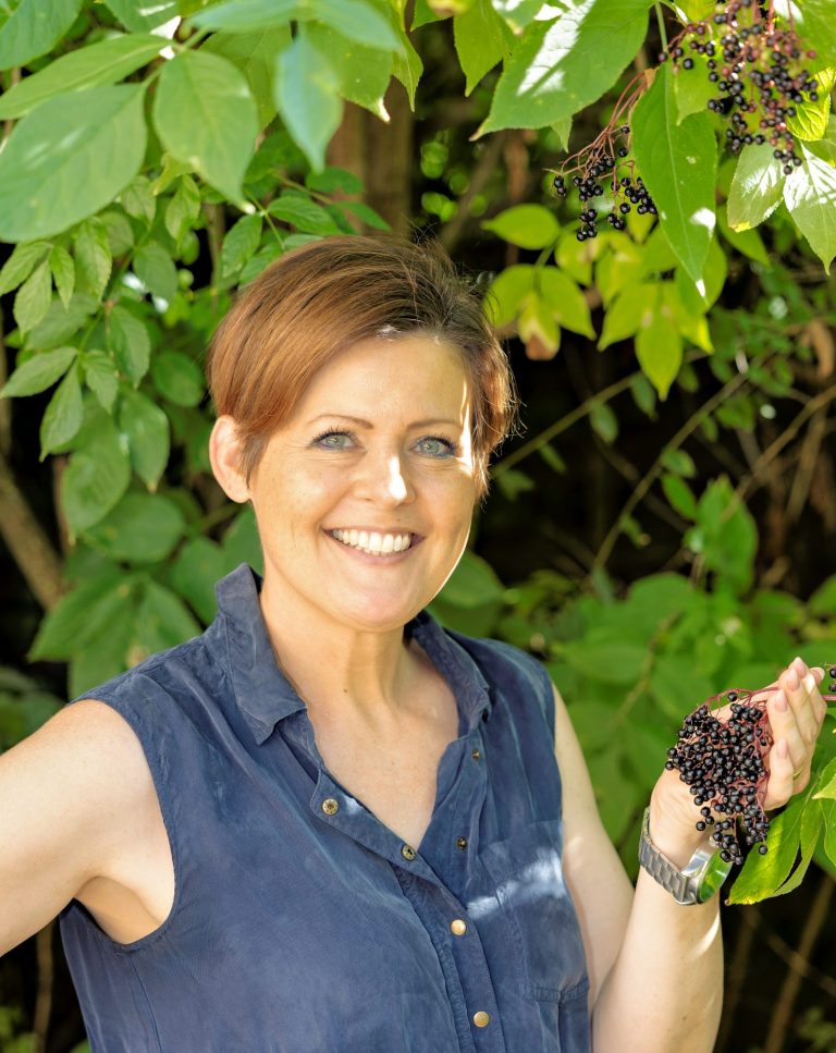 Naturheilkunde Kronberg - NaturaPathie Yasmin van der Heijden sitzt in der Praxis an ihrem Schreibtisch und lächelt in die Kamera